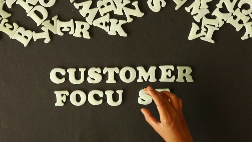 A person spelling Customer Focused With Plastic Letters