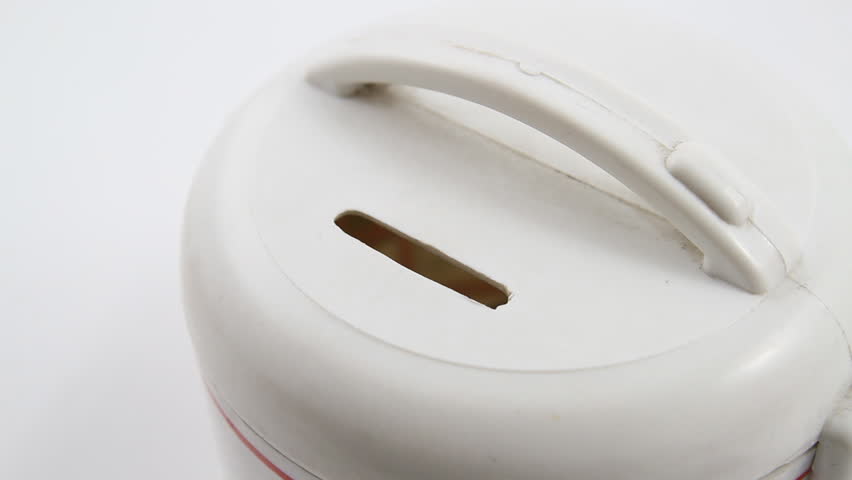 Hand is inserting a coin into piggybank in white background