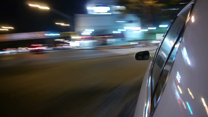 Driving a car time-lapse. Night, Camera gripped on the side / reference. POV - point of view. White car ride. City, blurred motion, fast driving. HD.