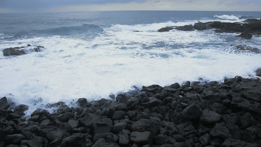 Waves crash on a black rock beach in Maui, Hawaii.