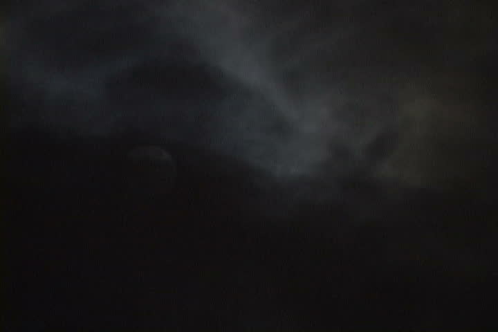 Time Lapse of Glowing, Full Moon at night as clouds move pass rapidly.