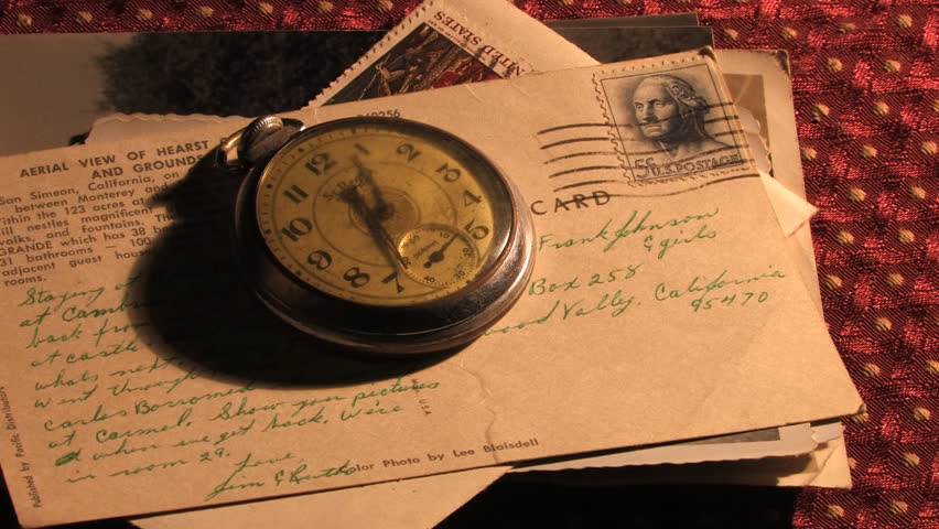Antique pocket watch on stack of old photos and postcards. 