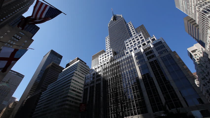 Pan over New York City buildings in front of dark blue sky beginning with american flag / HD1080 / 29.97fps