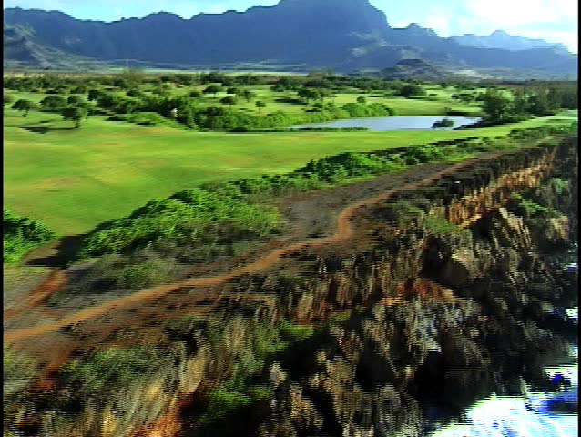 Aerial footage of Hawaii golf course with majestic mountains in the distance.