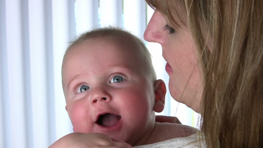 Mother hold her playful baby while he smiles and giggles