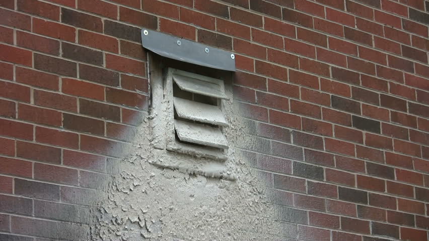 Brick wall with dirty exhaust vent with white waste stuck to the wall