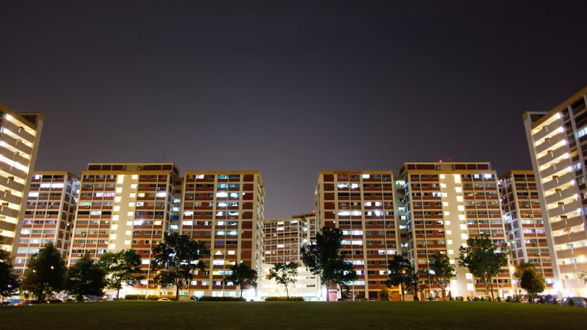 Timelapse video of night scene twinkling lights of residential apartment flats in Singapore (also known as HDB flats). Interesting patterns of lights turning on and off, with the occasional car trails