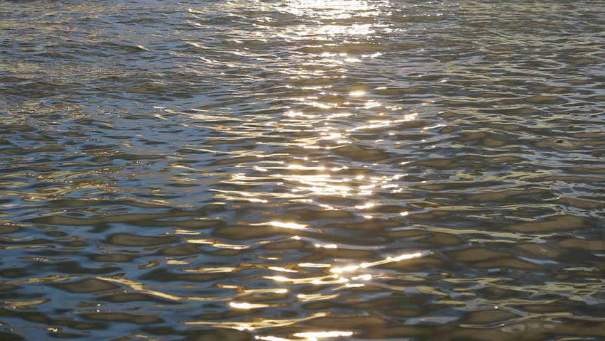 Waves in sunset, slowly defocused to abstract charming dancing lights