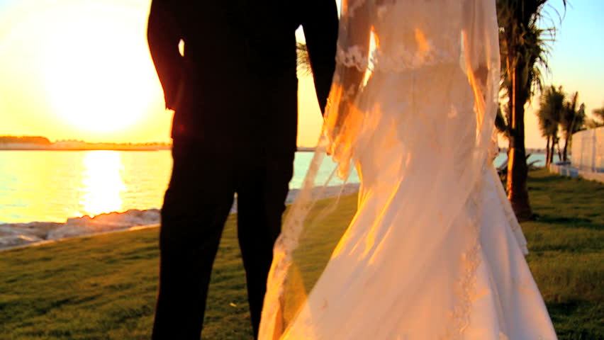 Young couple walking the beach after their tropical wedding ceremony