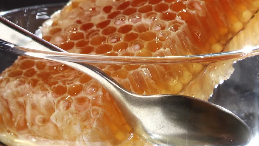 Closeup of honey pouring on the honeycombs