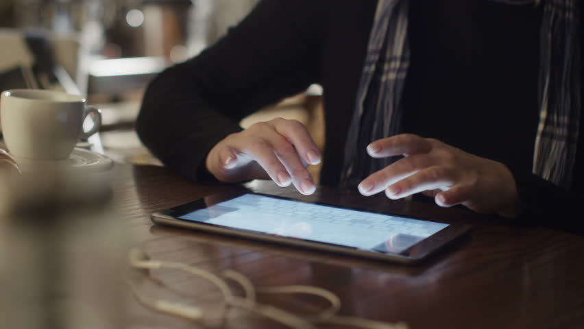 Woman Typing on Tablet PC in Coffee Shop. Shot on RED Digital Cinema Camera in 4K (ultra-high definition (UHD)), so you can easily crop, rotate and zoom, without losing quality.