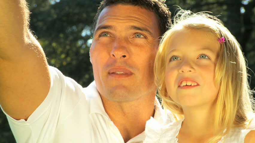 Young father tenderly holding his daughter while outdoors on a summers day