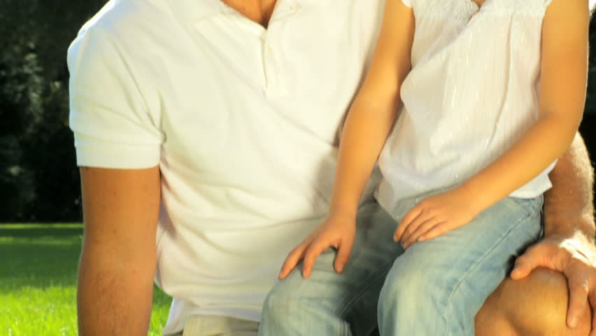 Young father tenderly holding his daughter while outdoors on a summers day