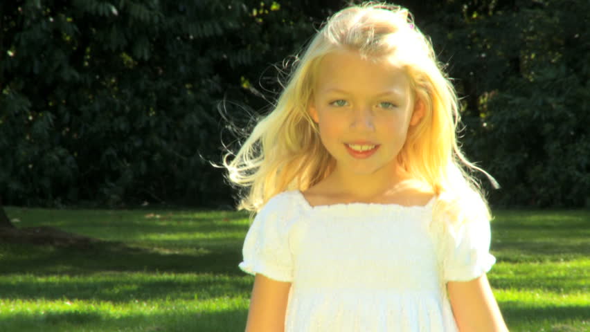 Portrait of pretty little blonde haired girl playing on a summers day
