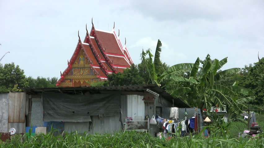 A shot of a run down shack in rural Thailand with a beautiful Buddhist temple in the background.