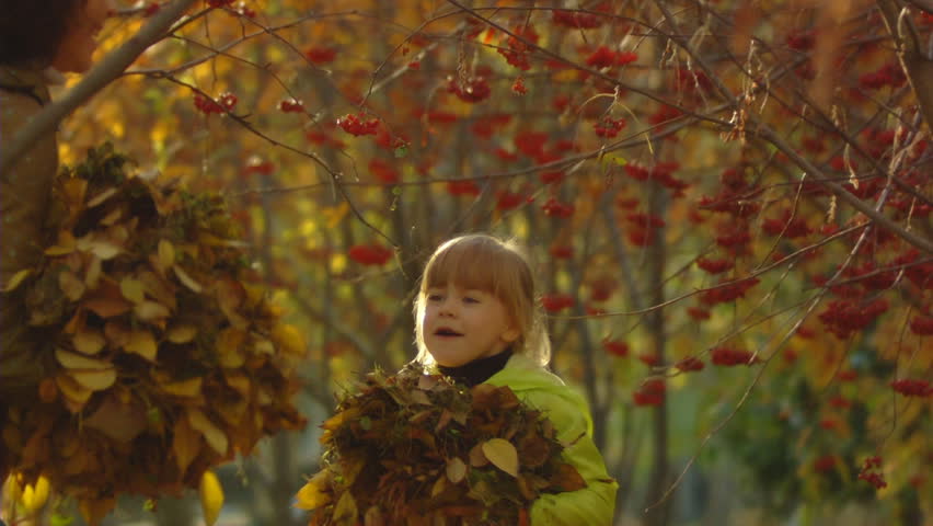 Sequence of slow motion shots happy mum and the little girl throw autumn leaves.