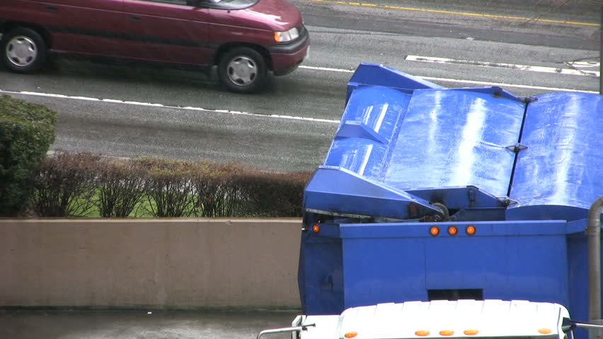 A recycling garbage truck dumps a new load of "recyclables" into it's bins. 