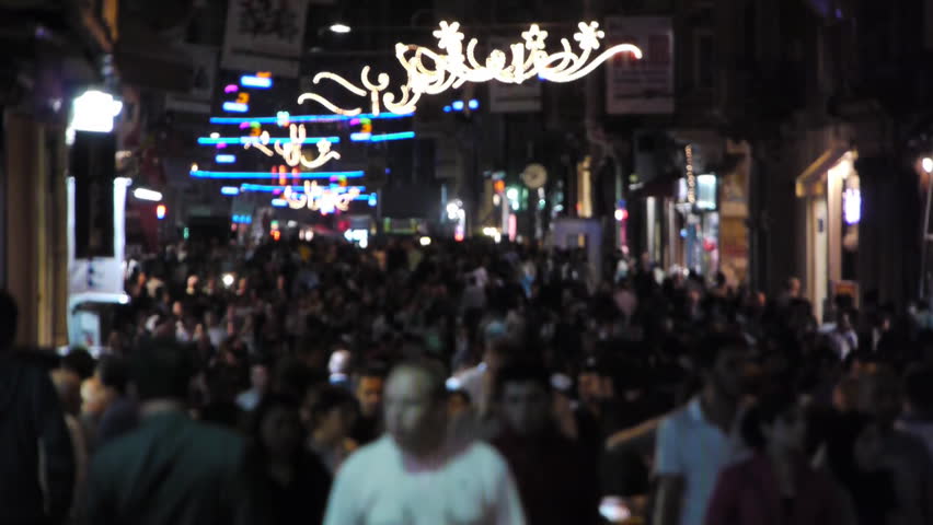 thousands of people walking on a Crowded street at night