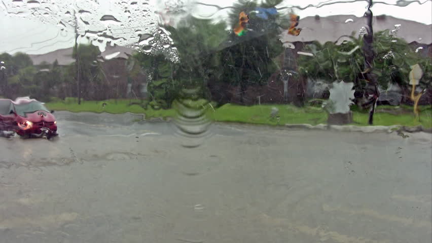 Video of flooded road intersection in San Antonio Texas. Massive rains causing many accidents. Cars and trucks passing. Residential area.
