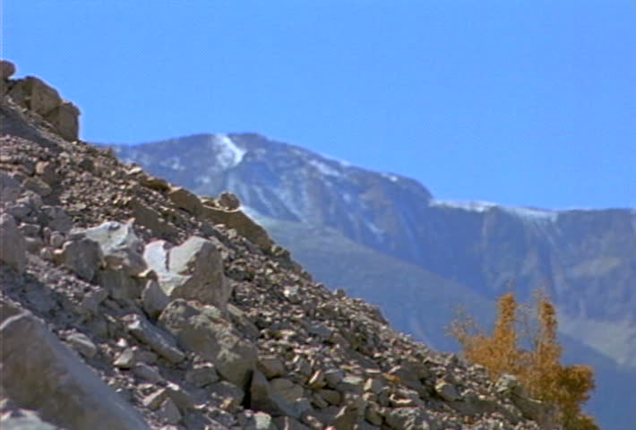 Boulders and smaller rocks roll and slide down a hill during a landslide.