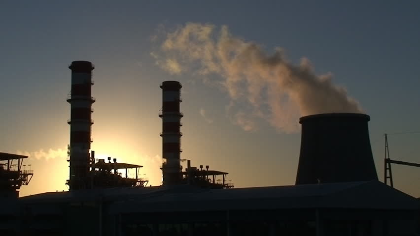 Power plant at sunset smokestacks emitting steam