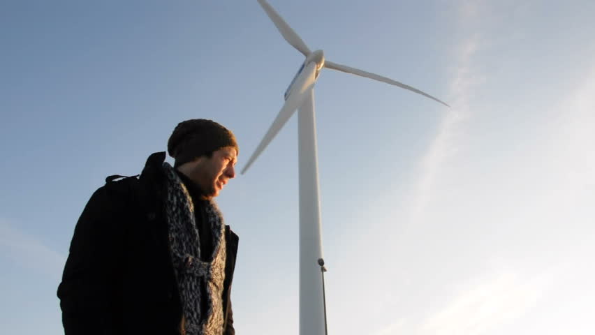 Smiling young man standing against large windmill on sunny day, low angle,HD 