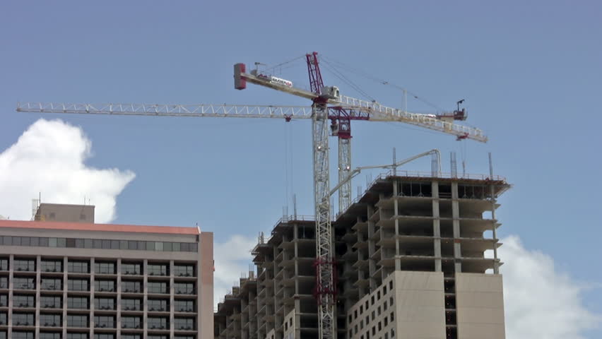 Video of large industrial building cranes lifting and lowering equipment and materials to top of skyscraper motel under construction in San Antonio, Texas.