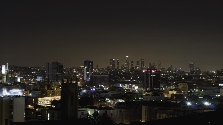 Wide aerial view of Los Angeles, with Hollywood in the foreground and downtown in the distance, between night and sunrise.