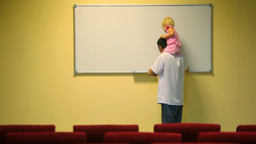 man holding little girl on shoulders cleans whiteboard in lecture room 