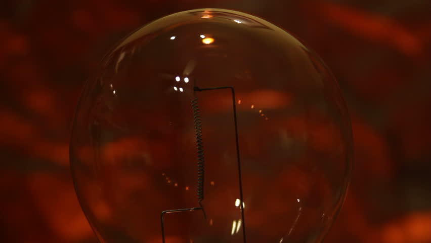 Close up of flashing high wattage incandescent bulb on a red textured background 