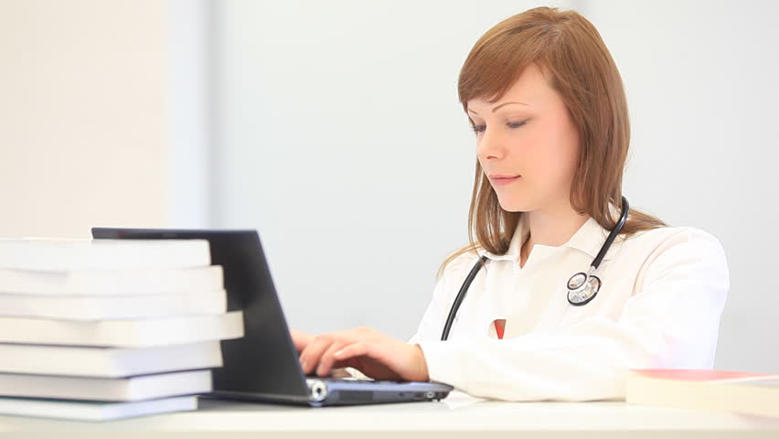 pretty young female doctor typing on a laptop computer