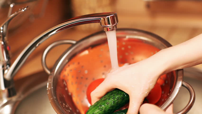 Young woman washing vegetables.