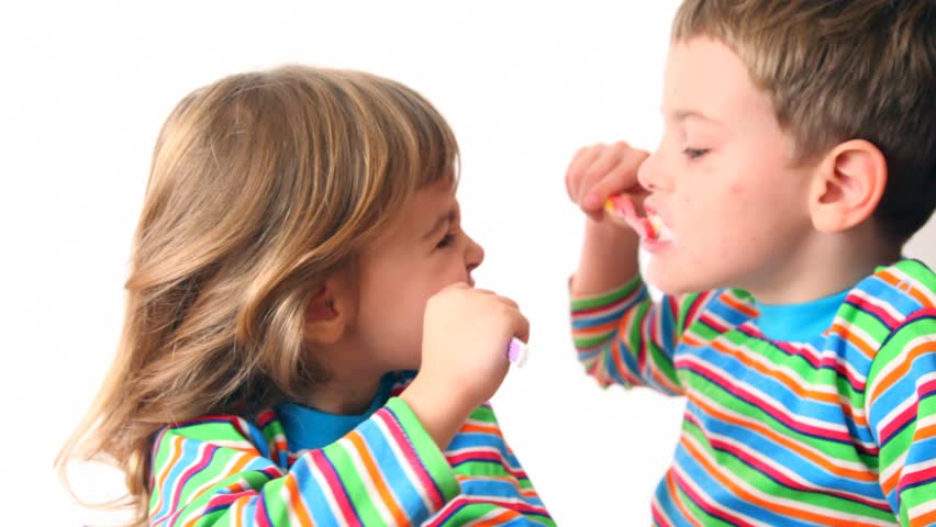 boy and girl brush teeth looking against each other, then turn and smile 