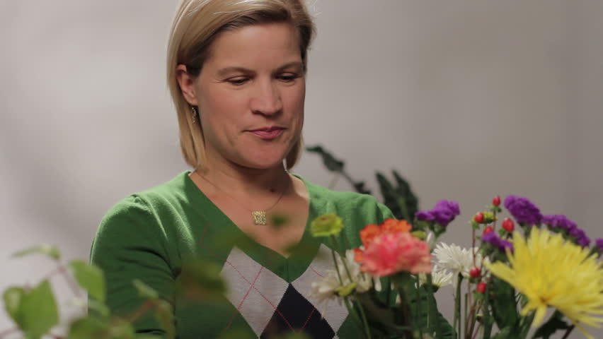 Woman arranging flowers, looking at camera