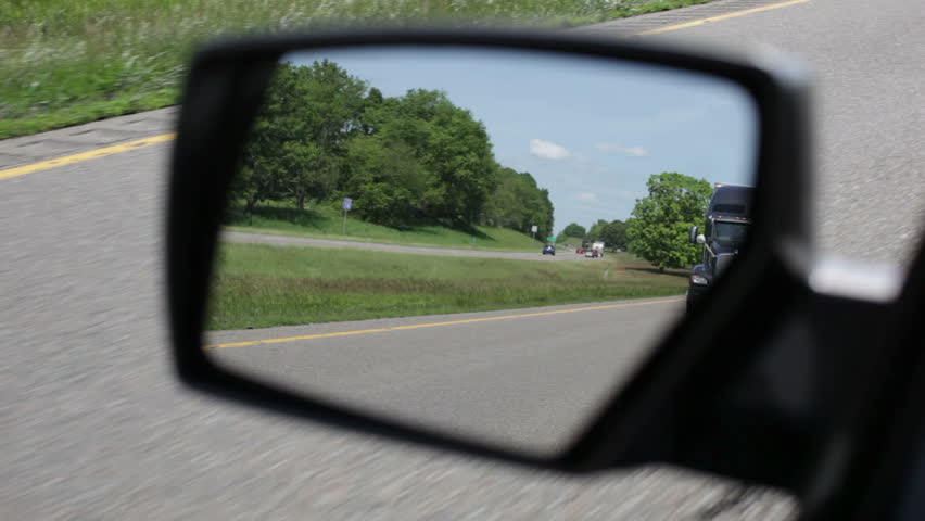 A black 18 wheeler seen in rearview mirror on interstate 81 in  Virginia