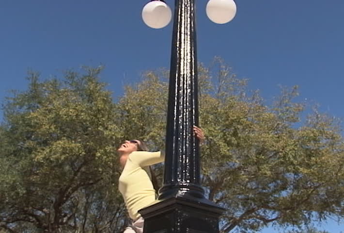 Pretty latina woman twirling around light post - slow motion