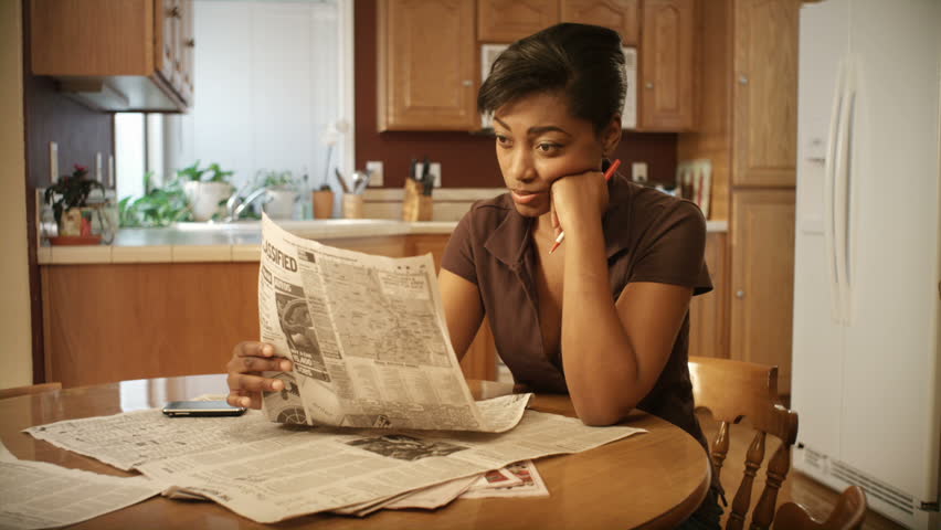 An African American woman performs various tasks around the house. 