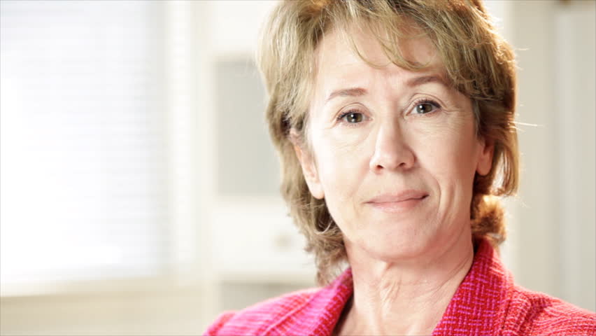 A mature businesswoman looks at the camera and smiles.