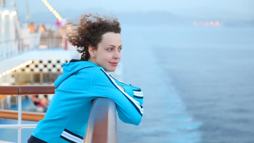 happy young woman stands on deck of cruise ship