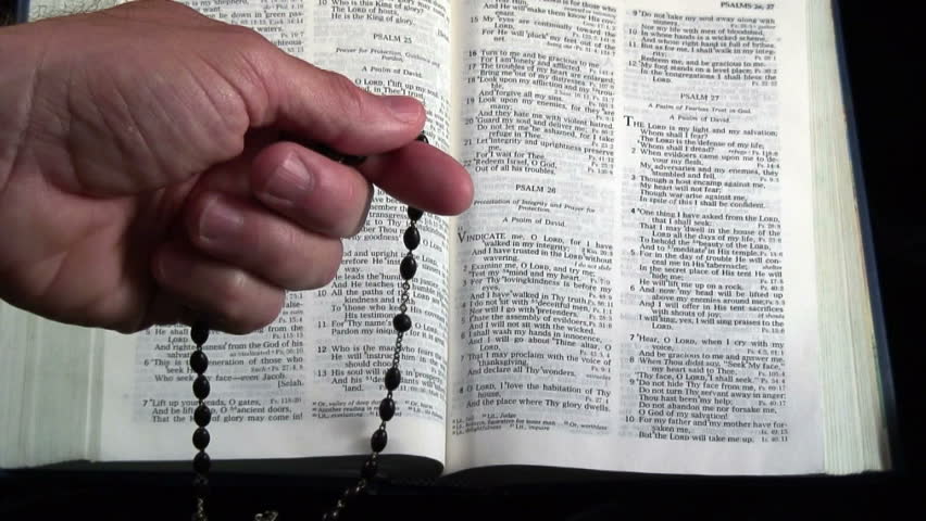 Man praying with the rosary, bible in the background