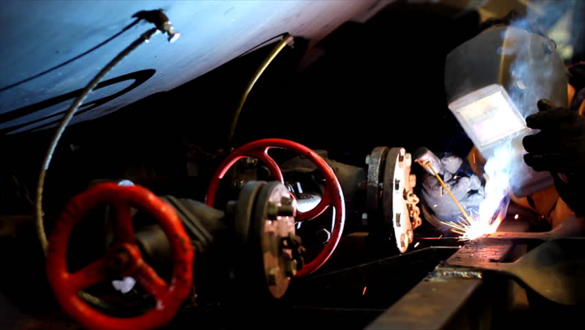 Welder at work in factory, welding tank