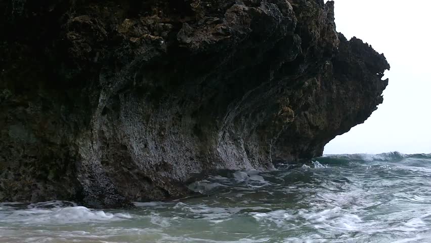 HD footage of strong waves on limestone rock and white sand beach eventually also reaching the camera, depicting how the ocean can erode rock through time.
