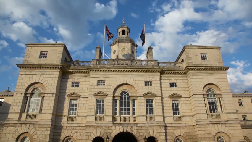 Two "union jack" flags waving on top of Horse Guard building in London on cloudy day