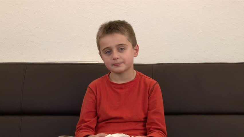 Young boy sneezes and blows his nose