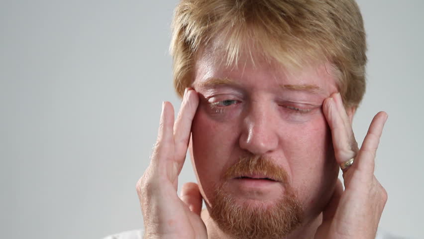Man rubs his temples to relieve his headache pain.