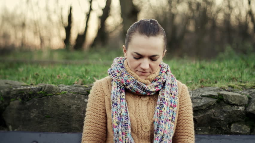 Sick woman in park using a tissue 