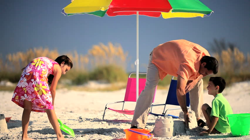 Young father & his children enjoying family time together  playing in the sand on a beach