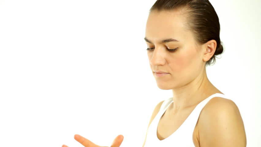 Woman applying moisturizer cream on her arm and smiling to camera, isolated on white 