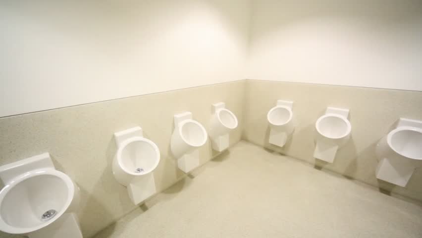 panning of empty mens toilet with row of urinals