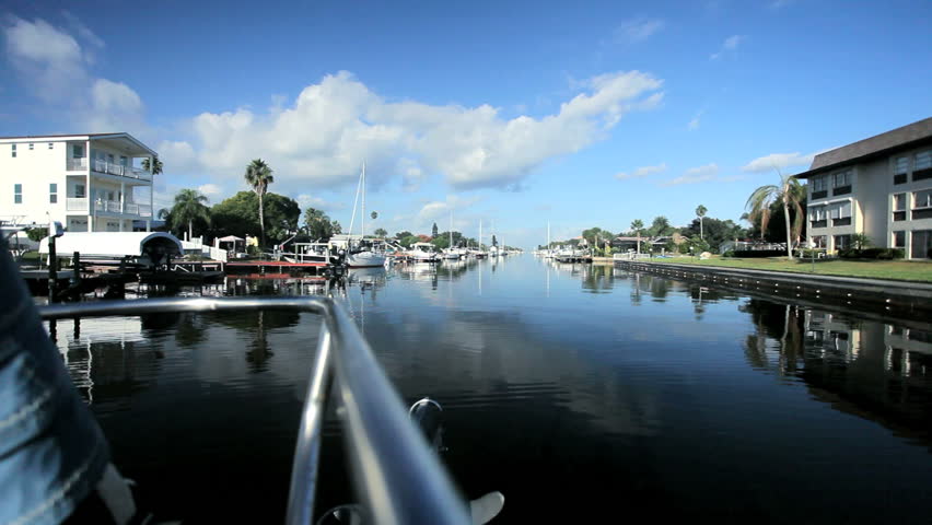 Bow of a luxury yacht sailing on waterways past luxury homes on a beautiful day